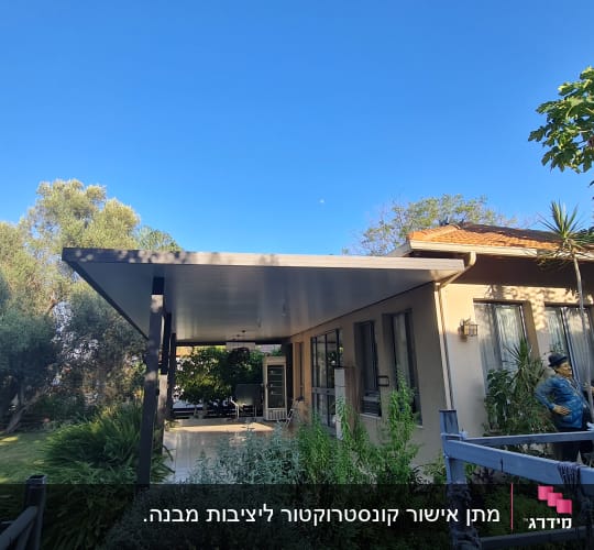 מרפסת עם גג מתכת, צמחייה מסביב, פסלים בחצר